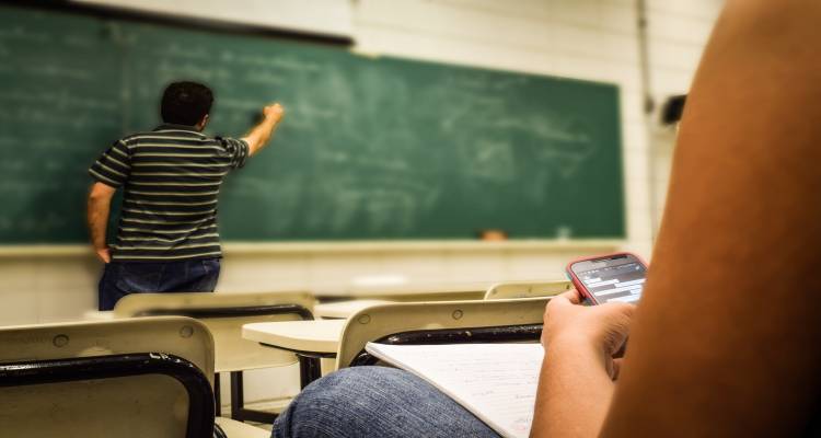 Mobiele telefoon in de klas Student met smartphone in klaslokaal